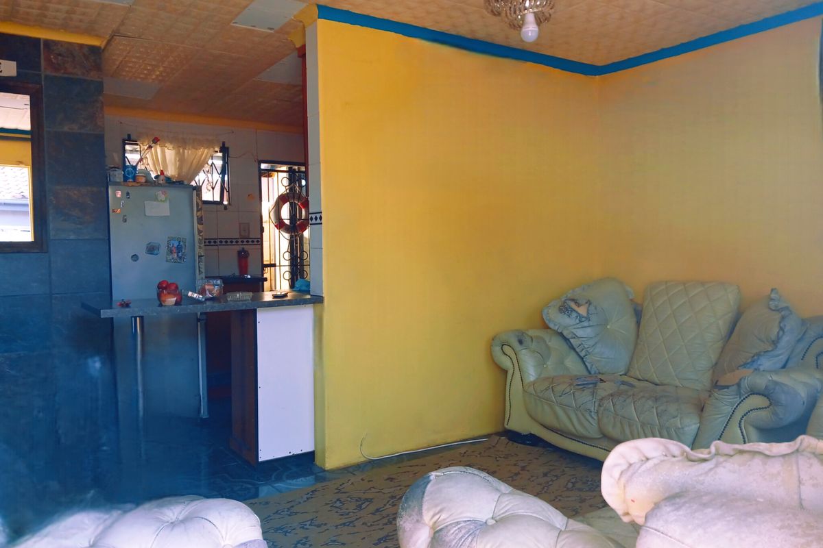 Open plan living area featuring a breakfast bar, tiled wall accents, and textured ceiling tiles, requiring cosmetic updates to modernize the space.