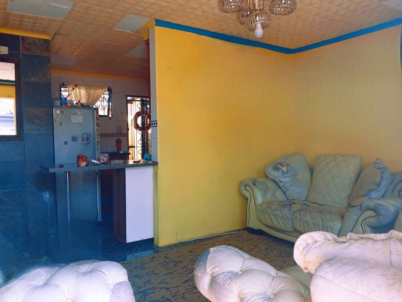 Open plan living area featuring a breakfast bar, tiled wall accents, and textured ceiling tiles, requiring cosmetic updates to modernize the space.