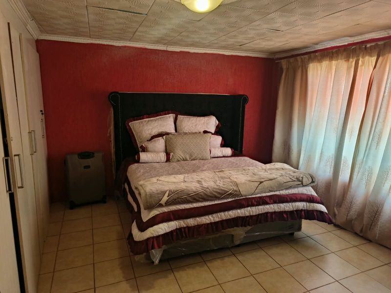 A bedroom featuring tiled flooring, built-in cupboards, and textured ceiling tiles, offering a functional space with potential for cosmetic updates.