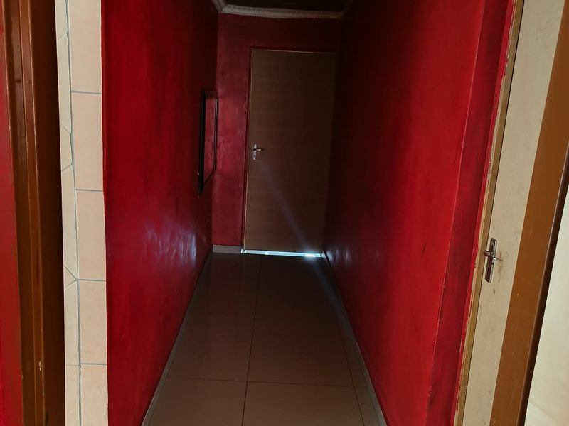 A narrow interior hallway featuring tiled flooring and wooden ceiling panels, currently showing signs of wear and requiring cosmetic updates.