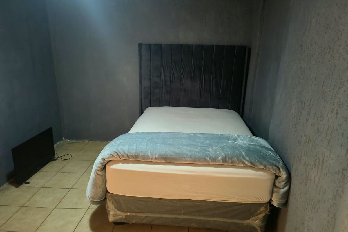 A bedroom featuring tiled flooring and dark textured walls, requiring finishing touches to the ceiling and wall surfaces.