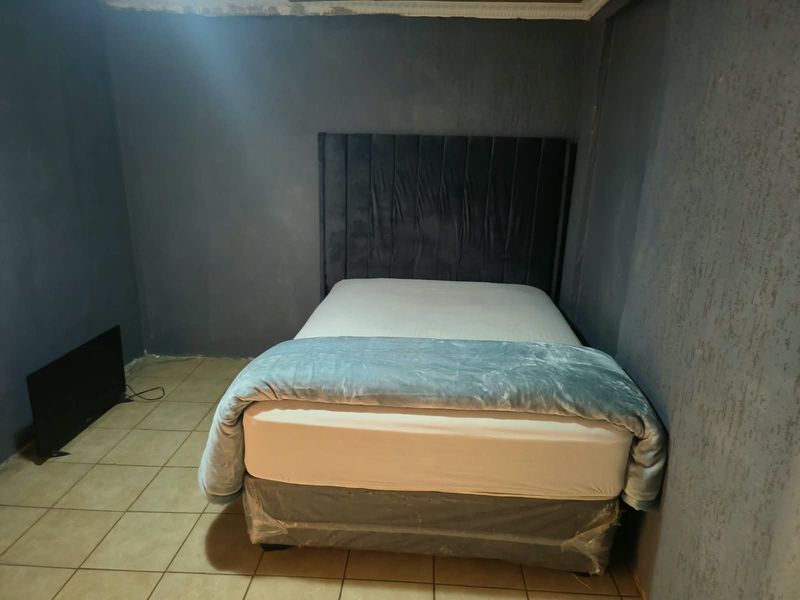 A bedroom featuring tiled flooring and dark textured walls, requiring finishing touches to the ceiling and wall surfaces.