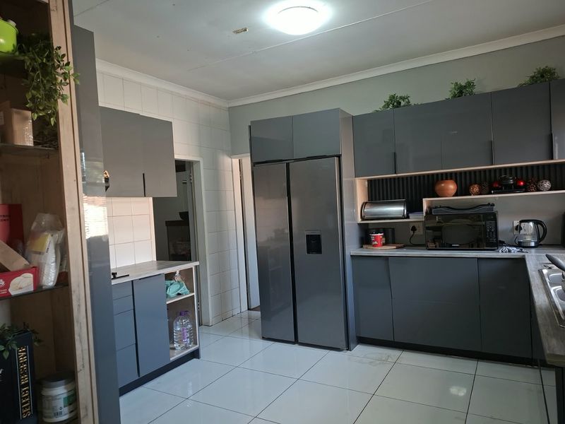 Modern kitchen featuring sleek grey cabinetry, tiled flooring, and a functional layout with integrated appliance spaces and a tiled backsplash.