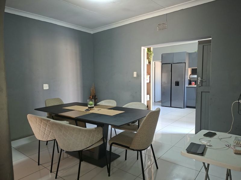 Open plan dining area featuring tiled flooring and coved ceilings, with a view into the adjacent modern kitchen space.