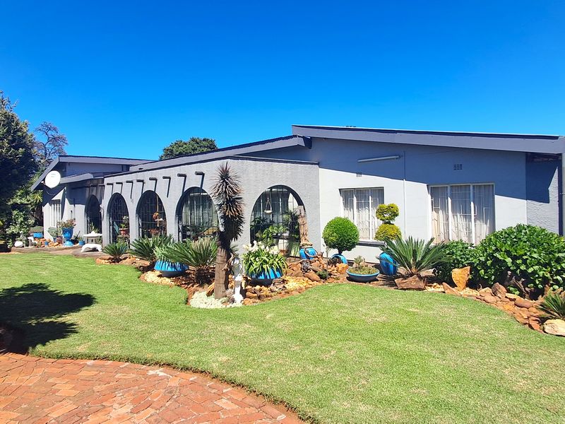 Rear view of the property featuring a well-maintained garden, brick paved pathway, and distinctive arched windows along the building facade.