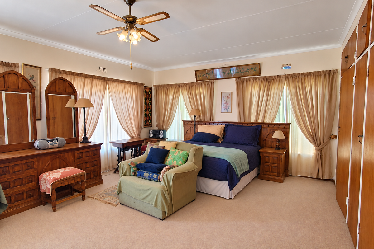 Spacious bedroom featuring neutral carpeting, a ceiling fan, and extensive built-in wooden cabinetry for ample storage.