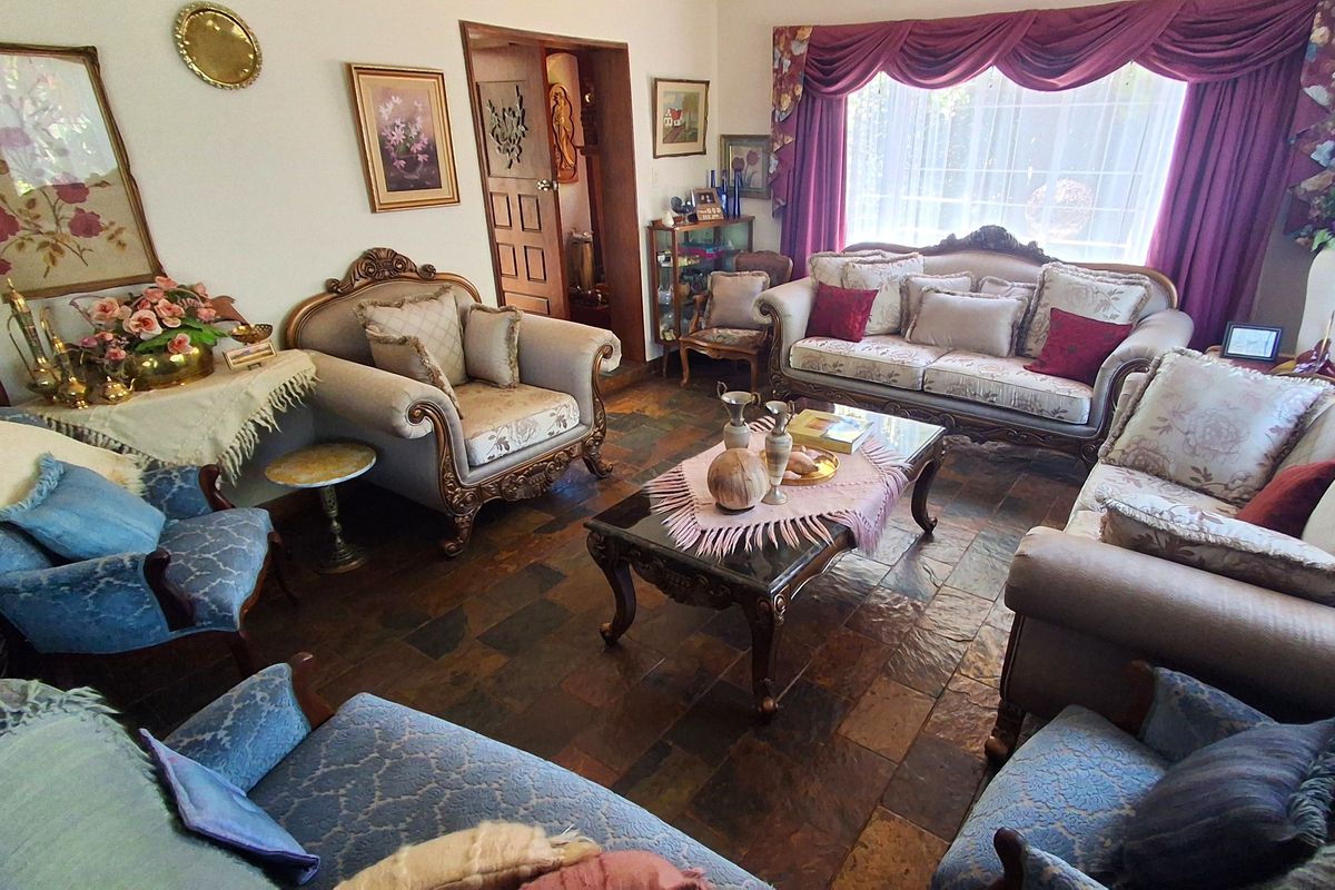A traditional living room featuring natural slate tile flooring and a large window with decorative drapery.