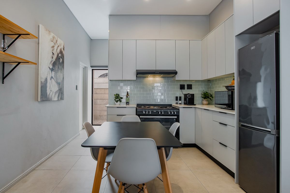 Modern kitchen featuring sleek cabinetry, subway tile backsplash, gas stove with extractor fan, and tiled flooring, offering a clean and functional cooking space.