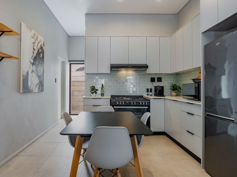 Modern kitchen featuring sleek cabinetry, subway tile backsplash, gas stove with extractor fan, and tiled flooring, offering a clean and functional cooking space.