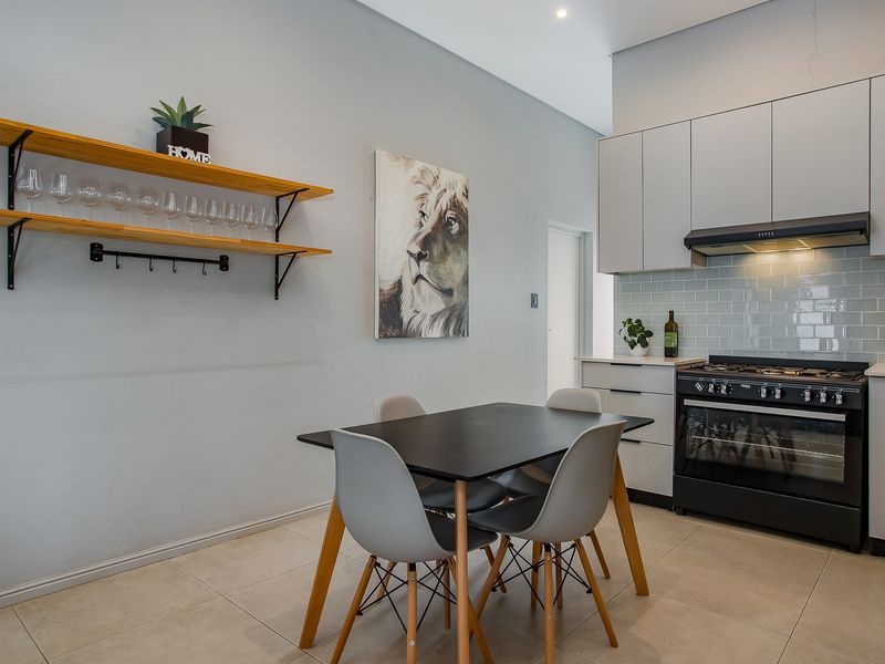 Modern open-plan kitchen and dining area featuring sleek cabinetry, a gas stove with extractor, and stylish subway tile backsplash.