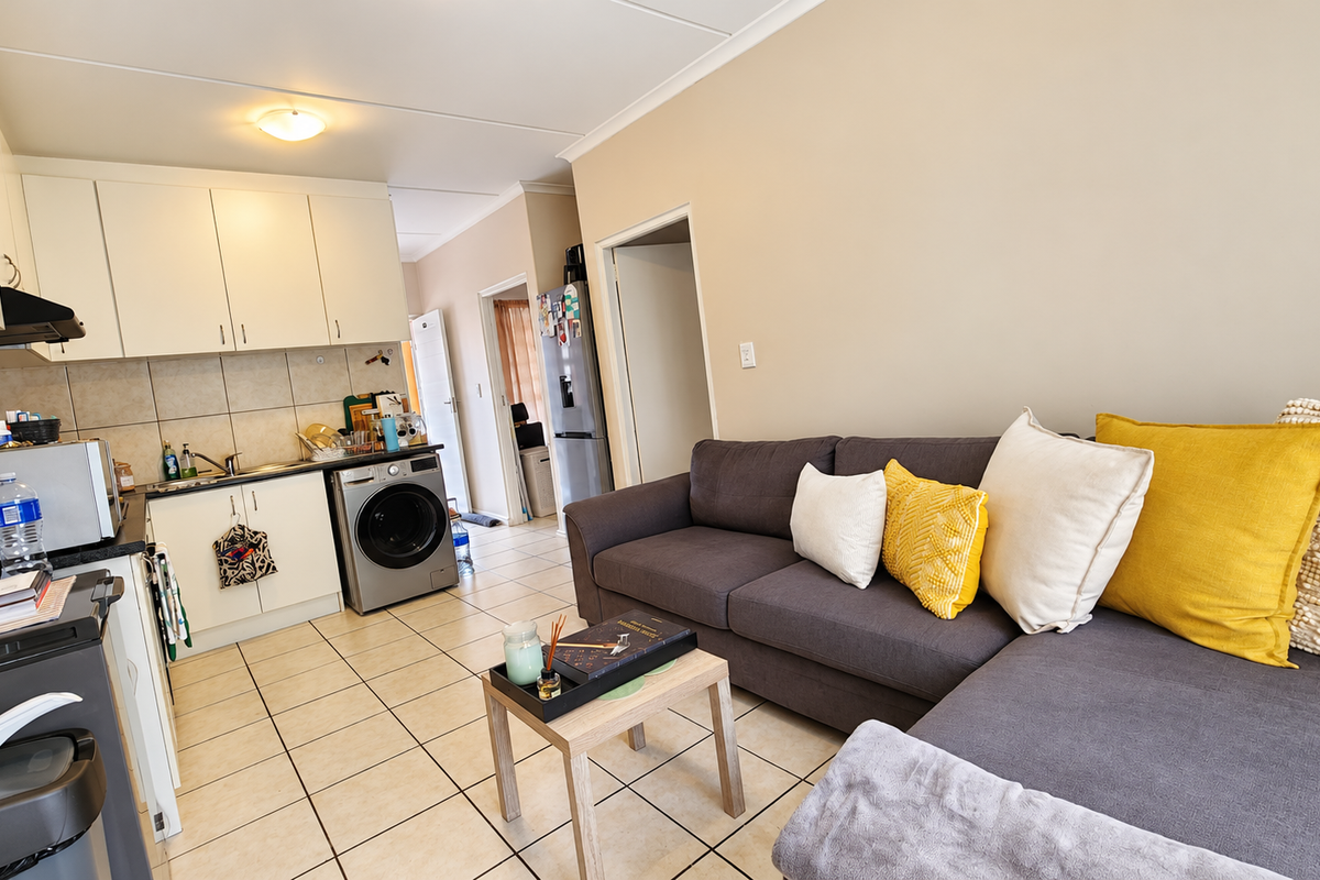 Open-plan living area featuring a functional kitchen with built-in cabinetry, tiled flooring, and a seamless transition to the lounge space.