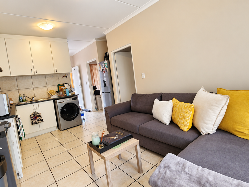 Open-plan living area featuring a functional kitchen with built-in cabinetry, tiled flooring, and a seamless transition to the lounge space.