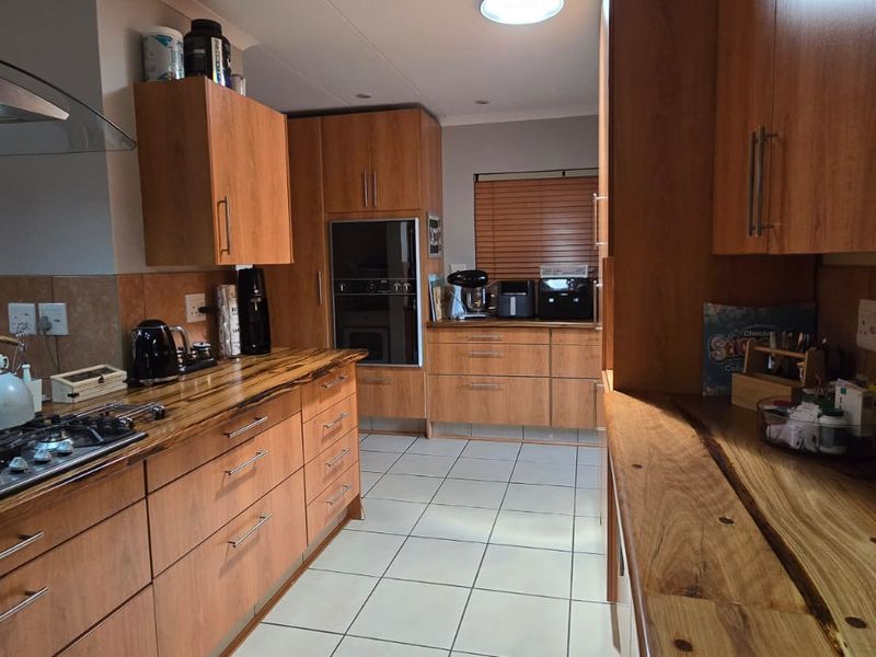 A functional kitchen featuring warm-toned wooden cabinetry, solid wood countertops, a gas hob with extractor, and a built-in oven.