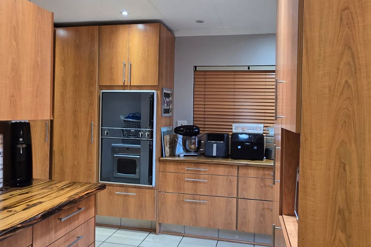 A functional kitchen featuring wood-finish cabinetry, built-in oven, and natural wood countertops with tiled flooring.