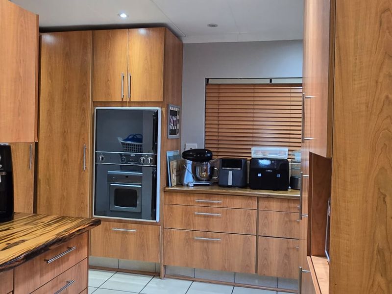 A functional kitchen featuring wood-finish cabinetry, built-in oven, and natural wood countertops with tiled flooring.