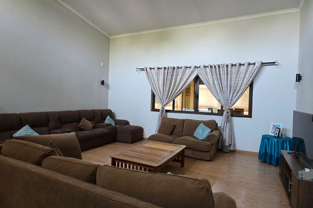 Spacious living room featuring high vaulted ceilings, laminate flooring, and a large window, offering a bright and airy atmosphere.