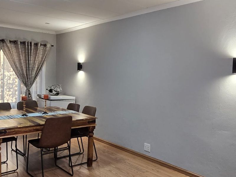 A well-maintained dining room featuring laminate flooring and modern wall-mounted lighting fixtures, creating a bright and inviting space for meals.