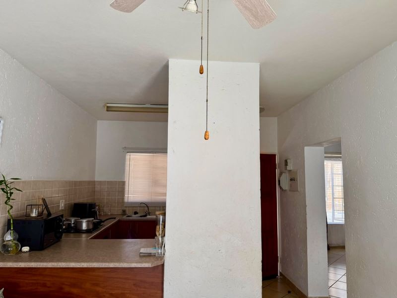 A functional kitchen area featuring built-in cabinetry, a tiled backsplash, and a breakfast counter, offering a practical layout for daily meal preparation.