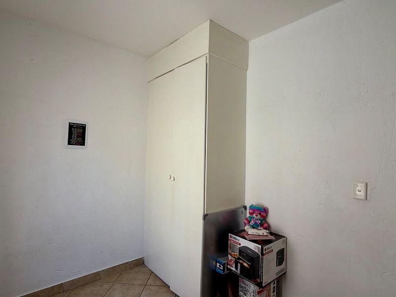 A simple bedroom featuring a built-in wardrobe and tiled flooring, offering a blank canvas for potential interior updates.