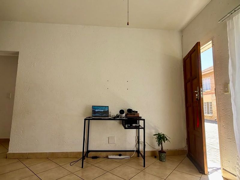 A bright, open-plan living area featuring tiled flooring and direct access to the exterior, offering a blank canvas for potential interior design updates.
