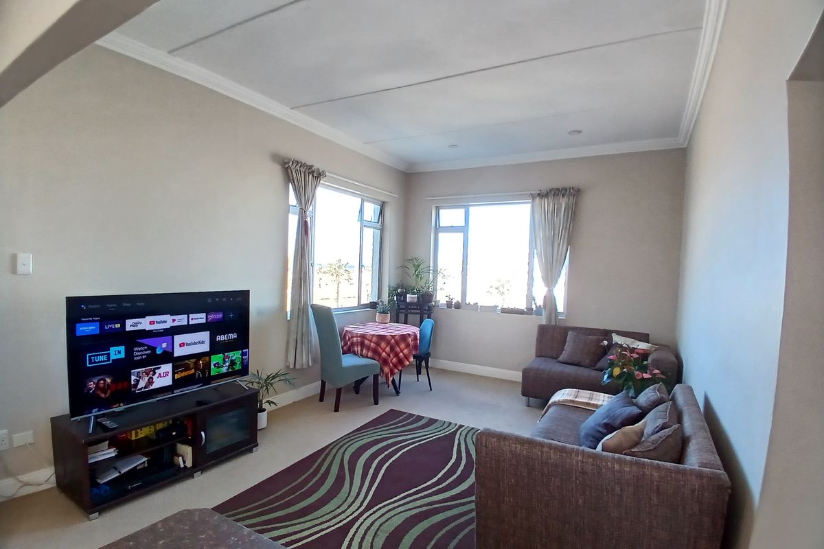A comfortable living room featuring coved ceilings, carpeted flooring, and large windows that provide ample natural light.