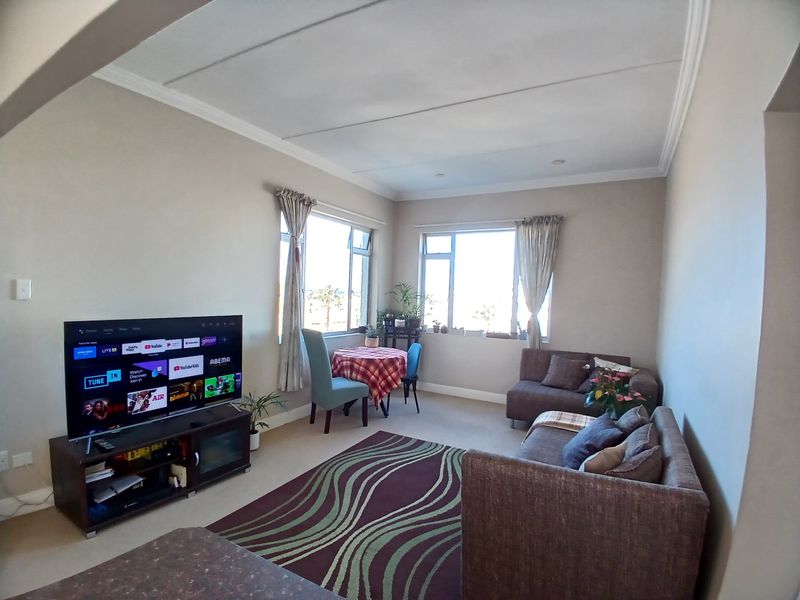 A comfortable living room featuring coved ceilings, carpeted flooring, and large windows that provide ample natural light.