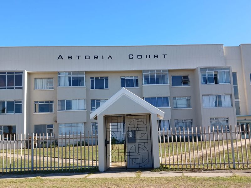 Front elevation of Astoria Court apartment building featuring a secure gated entrance, multi-story facade, and established casement windows.