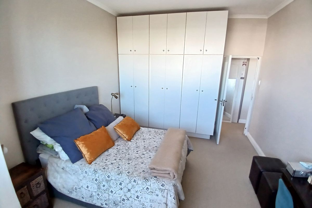A well-maintained bedroom featuring neutral walls, carpeted flooring, and extensive floor-to-ceiling built-in cupboards providing ample storage space.