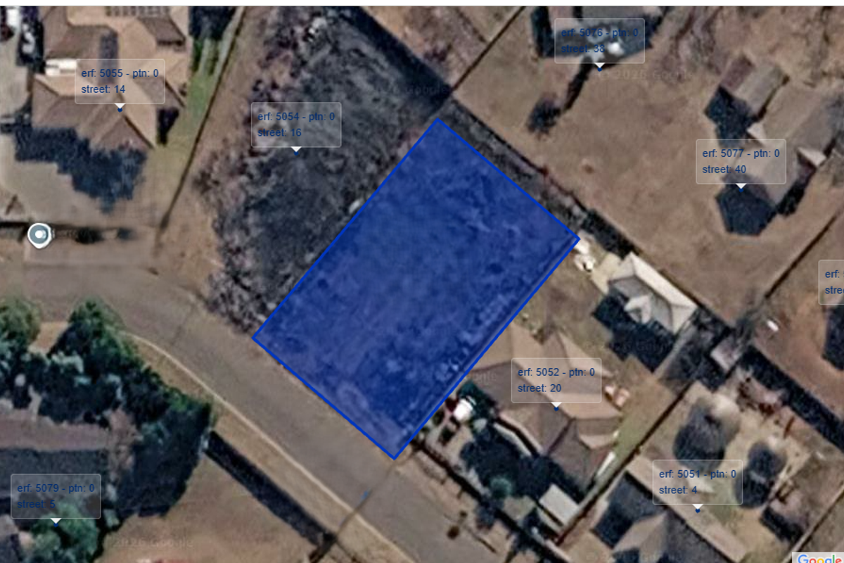 An aerial satellite view showing the vacant residential plot highlighted in blue within an established suburban neighborhood.