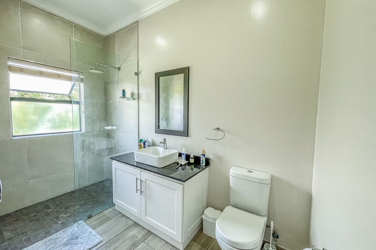 A modern bathroom featuring a glass-enclosed walk-in shower, a vanity with a vessel sink, and a standard toilet with tiled flooring.