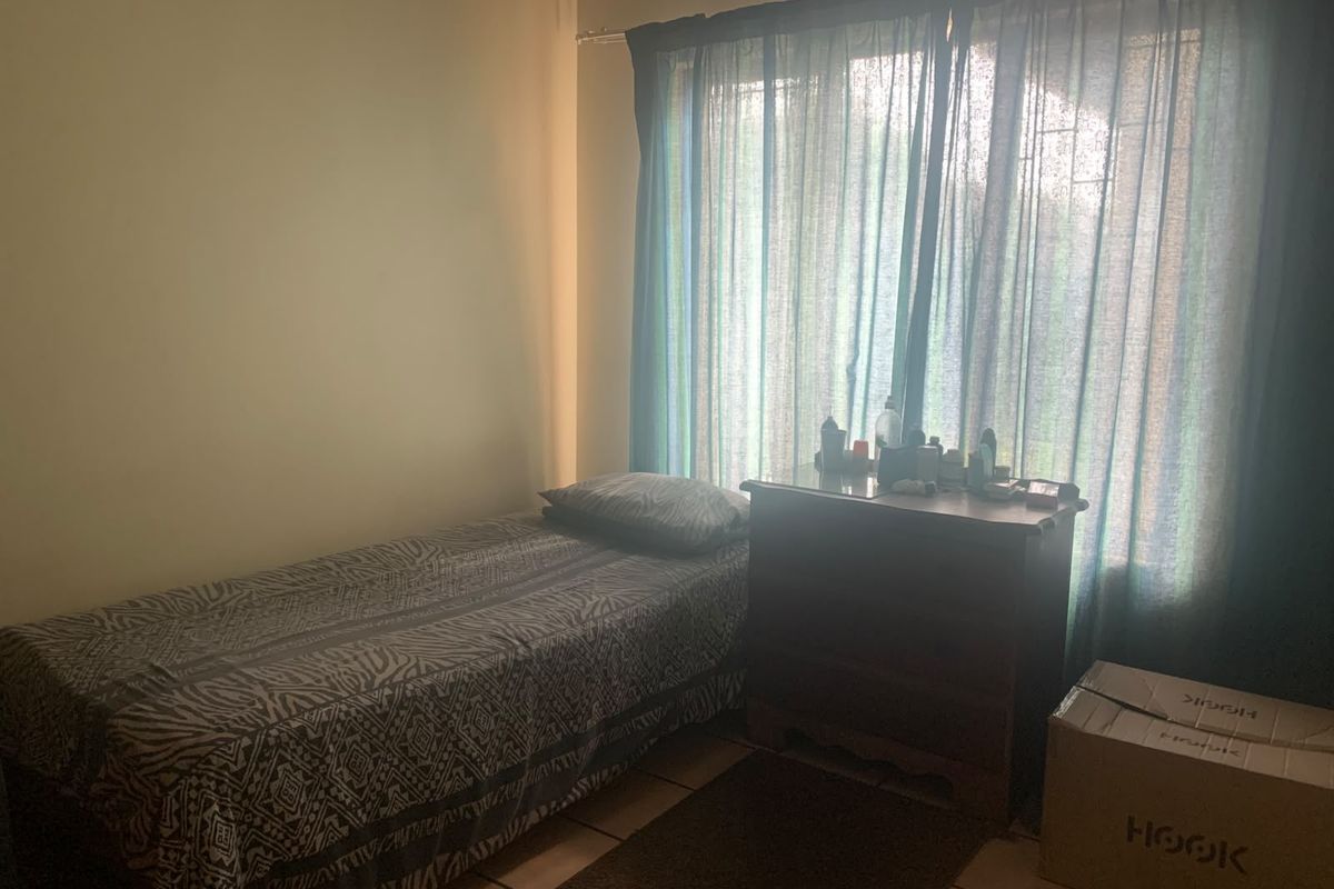 A bedroom featuring tiled flooring and a window with a curtain rod, offering a functional space with natural light.