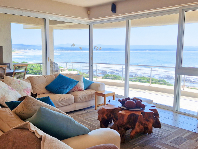 Spacious living room featuring expansive sliding glass doors that offer panoramic ocean views and direct access to a private balcony.