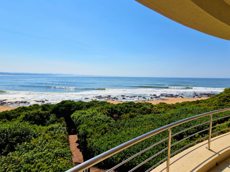 A stunning elevated ocean view from a private balcony featuring a modern stainless steel balustrade and direct access to the coastal landscape.