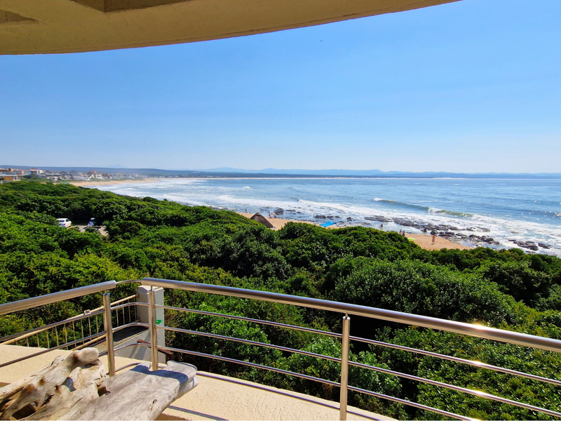 A scenic elevated view of the coastline and ocean from a balcony featuring a modern stainless steel balustrade.
