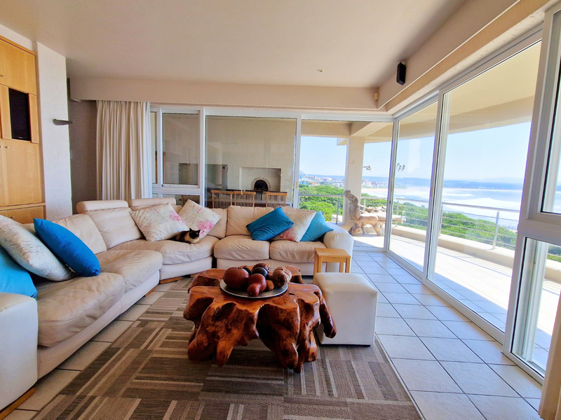 Spacious living room featuring built-in cabinetry, large sliding glass doors, and expansive ocean views, leading out to a covered patio area.