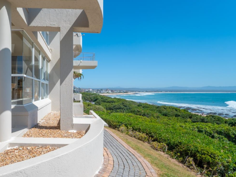 Stunning coastal view featuring a paved walkway, modern architectural columns, and expansive ocean vistas.