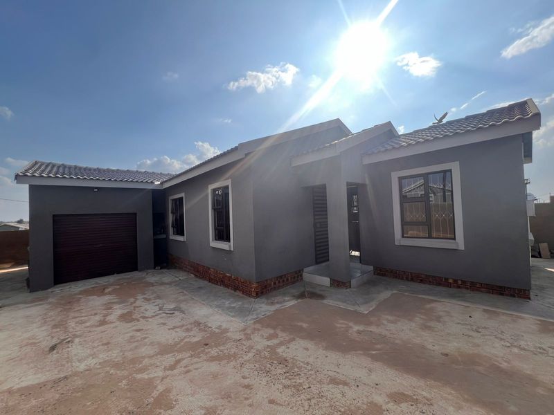 Front elevation of a modern single-story house featuring a grey rendered facade, tiled roof, integrated garage, and security-fitted windows.