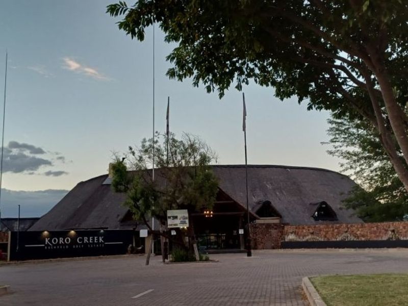 Front view of the Koro Creek Bushveld Golf Estate clubhouse featuring a traditional thatched roof and stone facade.
