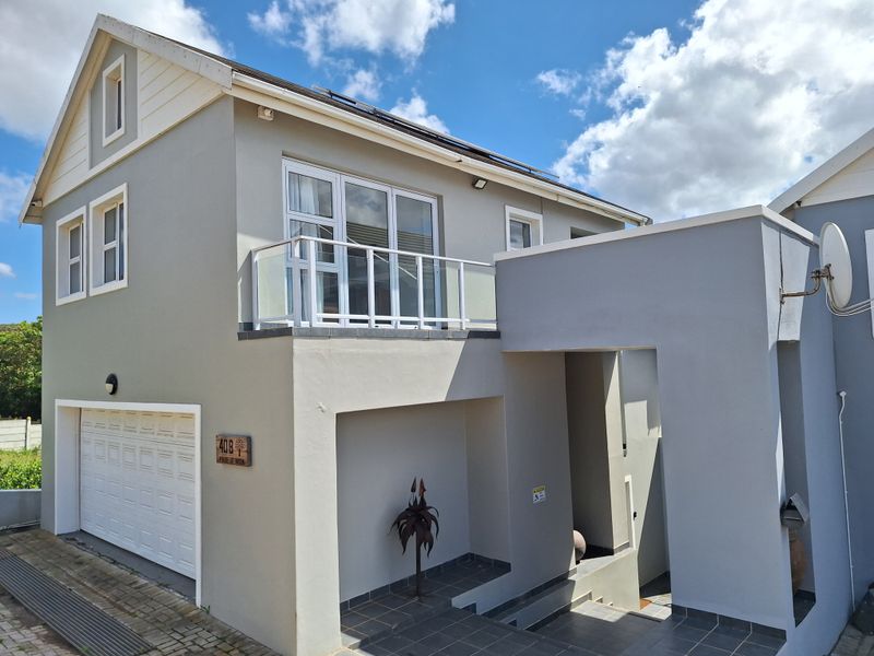 Front elevation of a modern duet property featuring a garage, a balcony with glass balustrade, and a tiled entrance area.