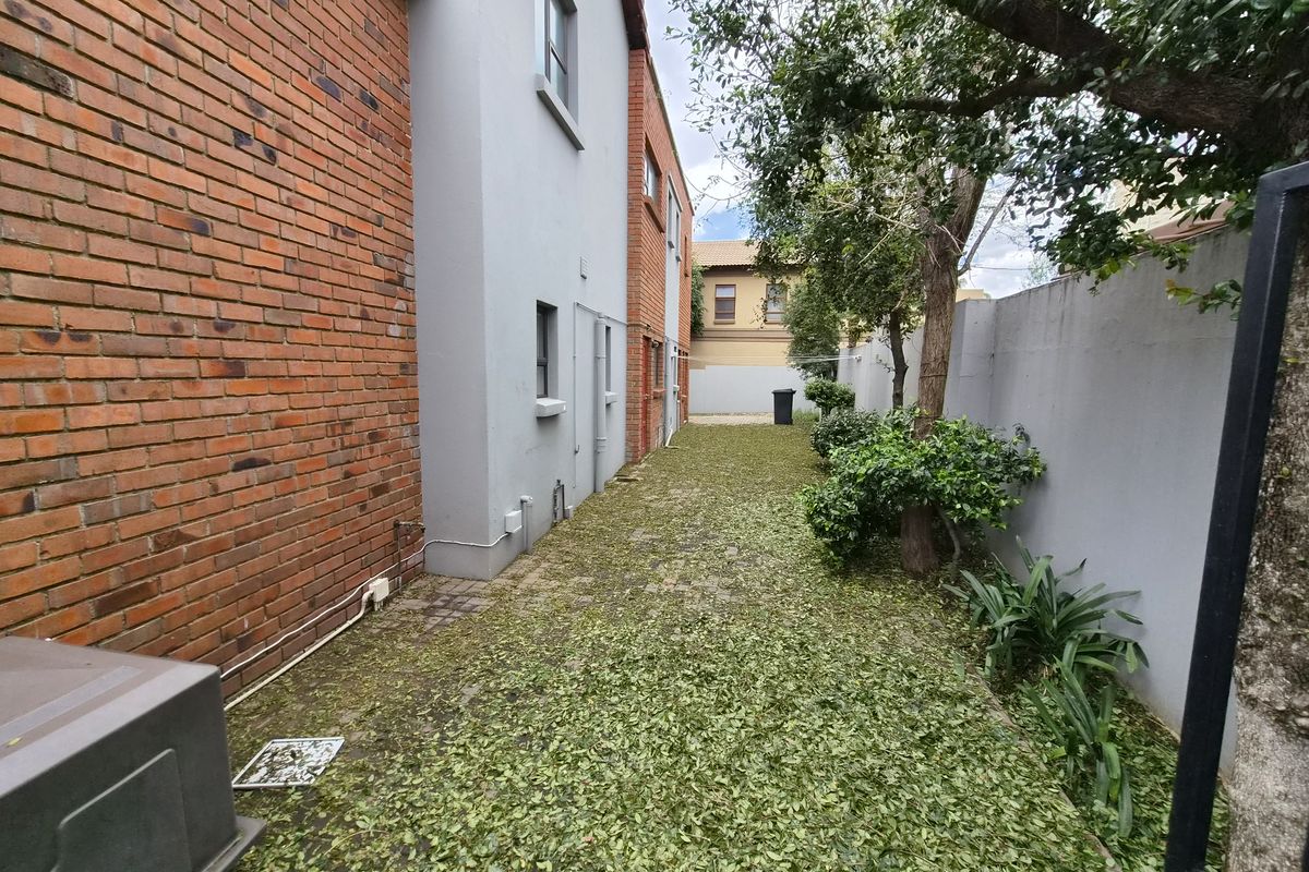 A side passage or rear exterior area featuring a mix of brick and plastered wall finishes with a paved walkway.
