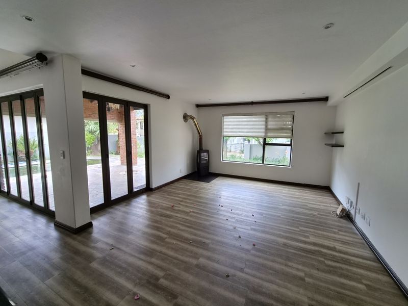 Spacious living area featuring laminate flooring, a built-in wood-burning fireplace, and large sliding glass doors providing direct access to the outdoor patio.