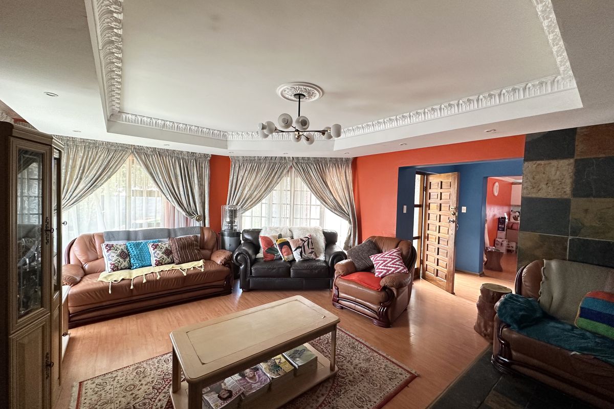 Spacious living room featuring ornate ceiling cornicing, a central ceiling rose, and a stone-tiled fireplace feature wall.