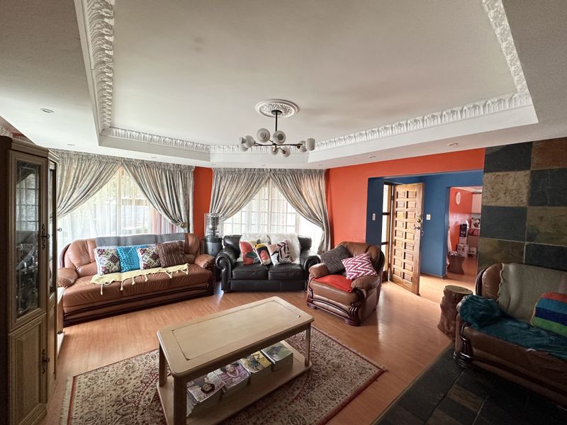 Spacious living room featuring ornate ceiling cornicing, a central ceiling rose, and a stone-tiled fireplace feature wall.