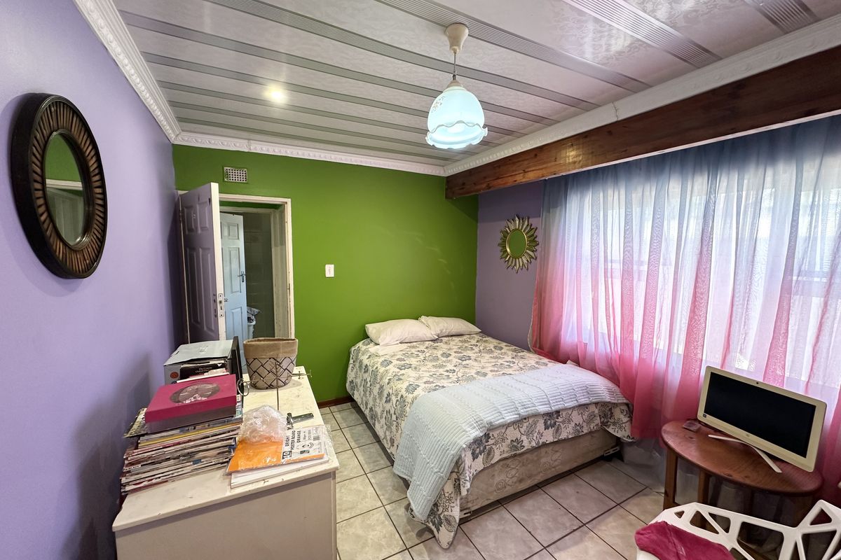 A bedroom featuring tiled flooring, a unique ceiling panel design with crown molding, and an exposed wooden beam accent.