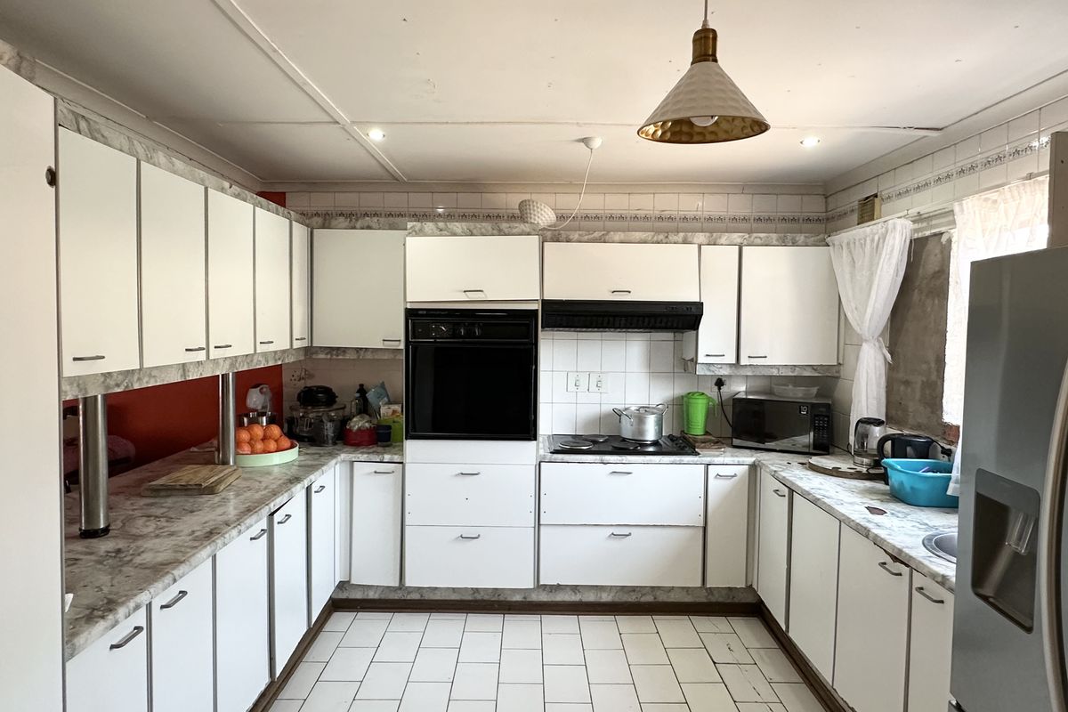 A functional kitchen featuring white cabinetry, laminate countertops, built-in oven, and hob, with tiled flooring and backsplash throughout.