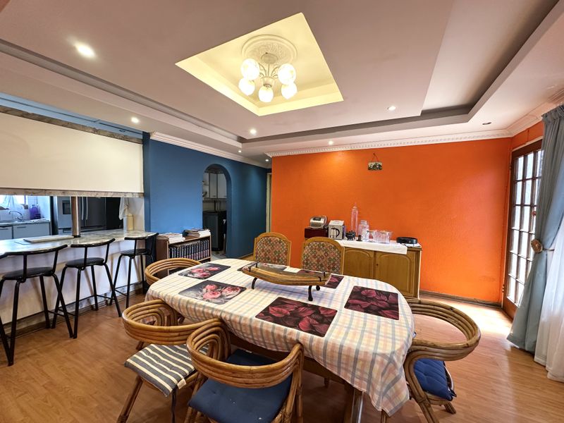 Open plan dining and kitchen area featuring a breakfast bar, recessed ceiling with lighting, and laminate flooring.