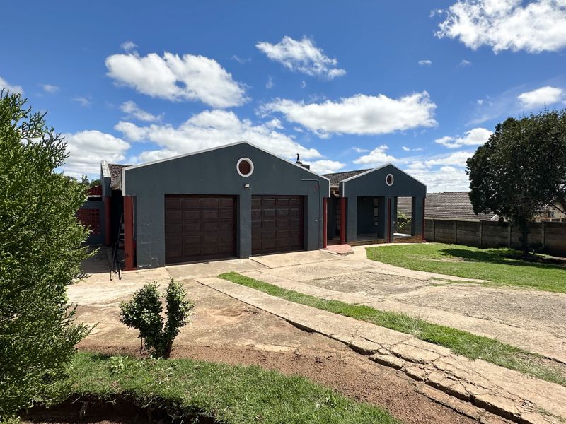 Front view of a residential property featuring a double garage, concrete driveway, and a covered entrance area with a tiled roof.