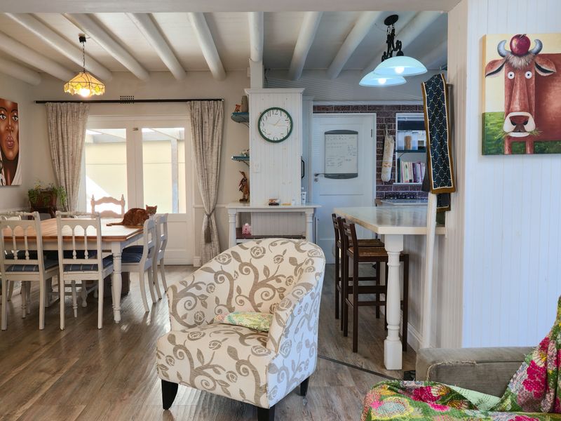 Open plan living and dining area featuring exposed ceiling beams, laminate flooring, and a breakfast bar connecting to the kitchen space.