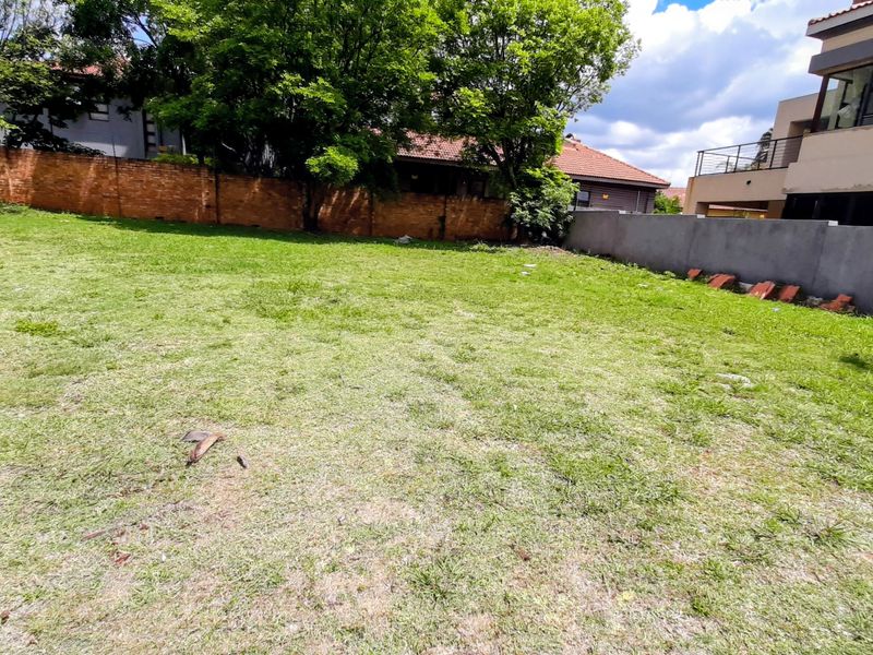 A spacious, level residential plot featuring established boundary walls and mature trees, offering a clear area ready for development.