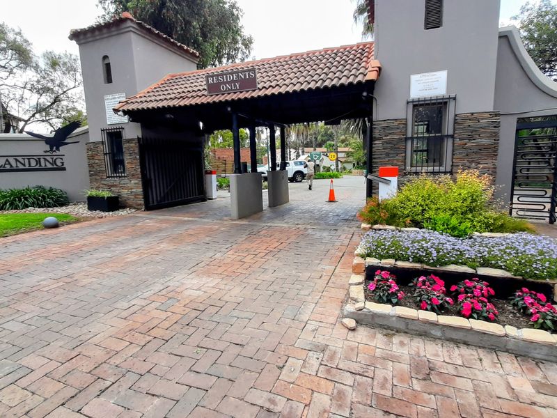The main entrance gate to Eagle's Landing residential estate, featuring a brick-paved driveway, security boom, and stone-clad pillars.